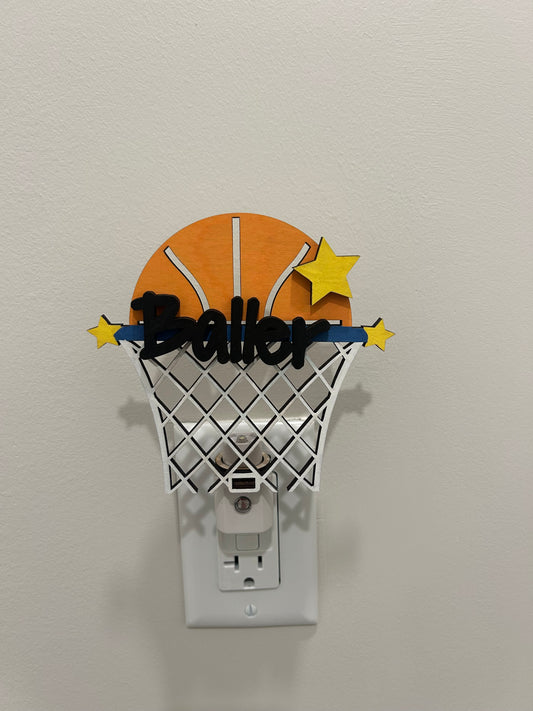 Decorative outlet cover shaped like a basketball hoop with stars and basketball decorations.