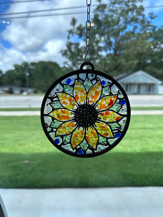 Decorative stained glass sun catcher with colorful sunflower design hanging on a window.