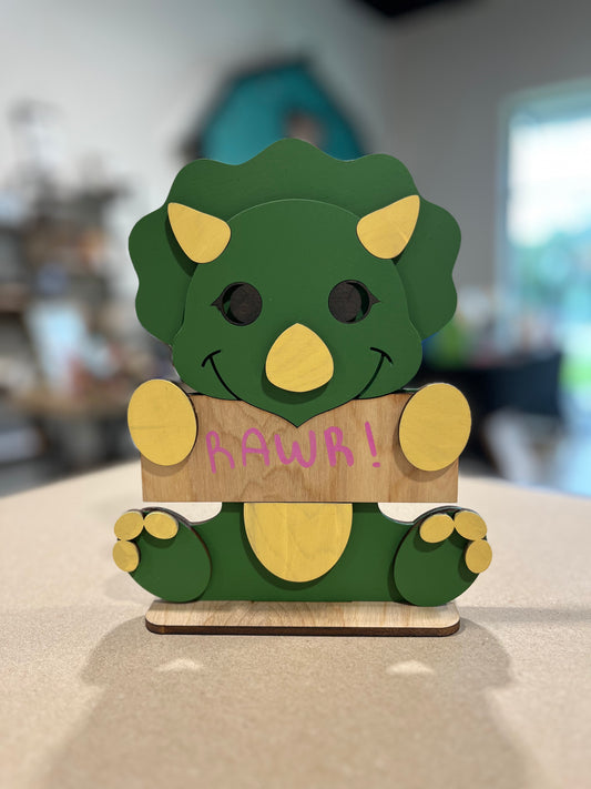 Green dinosaur child's decoration holding a 'RAWR!' customizable sign.