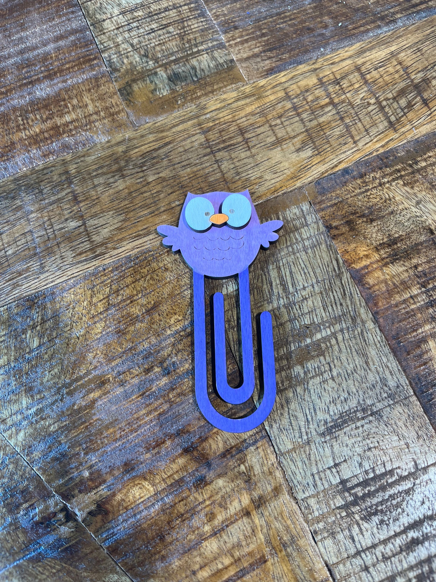 Purple owl shaped book mark on a wooden surface