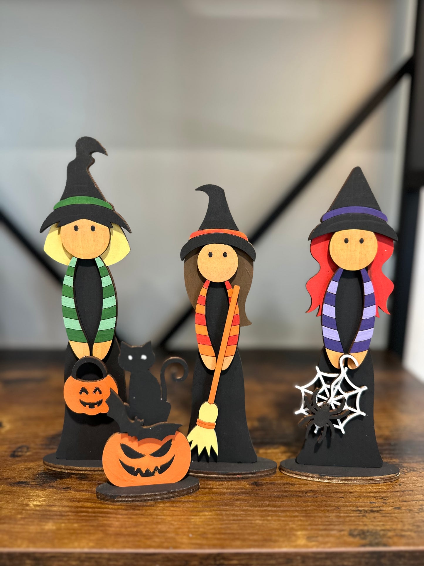 Three Halloween-themed witch figurines with pumpkins, a black cat, and brooms.