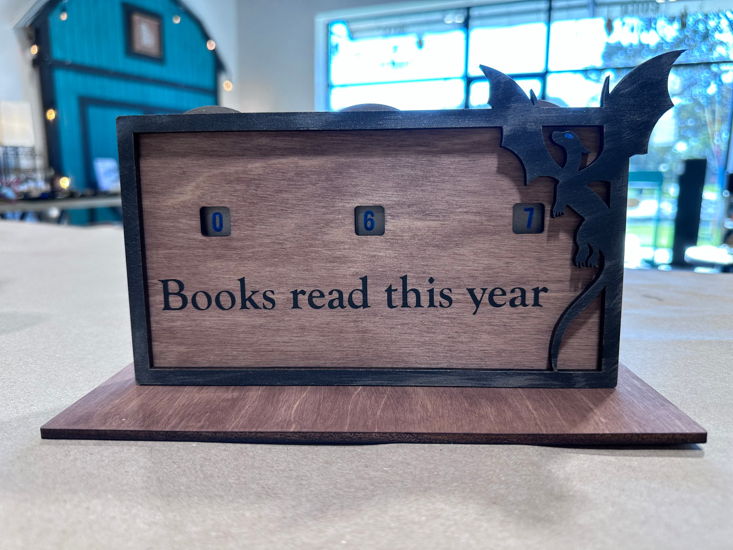 Wooden book counter with 'Books read this year' display on the stained surface, and dragon frame around it.