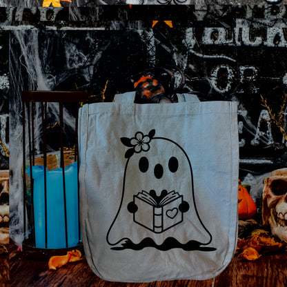 Design option a simple ghost holding a book with a heart on it. The ghost has a flower on its head.