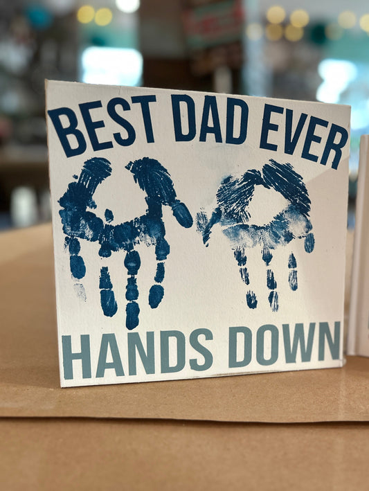 Create a custom sign for dad that says, "Best Dad Ever Hands Down" with your child's handprints in the center