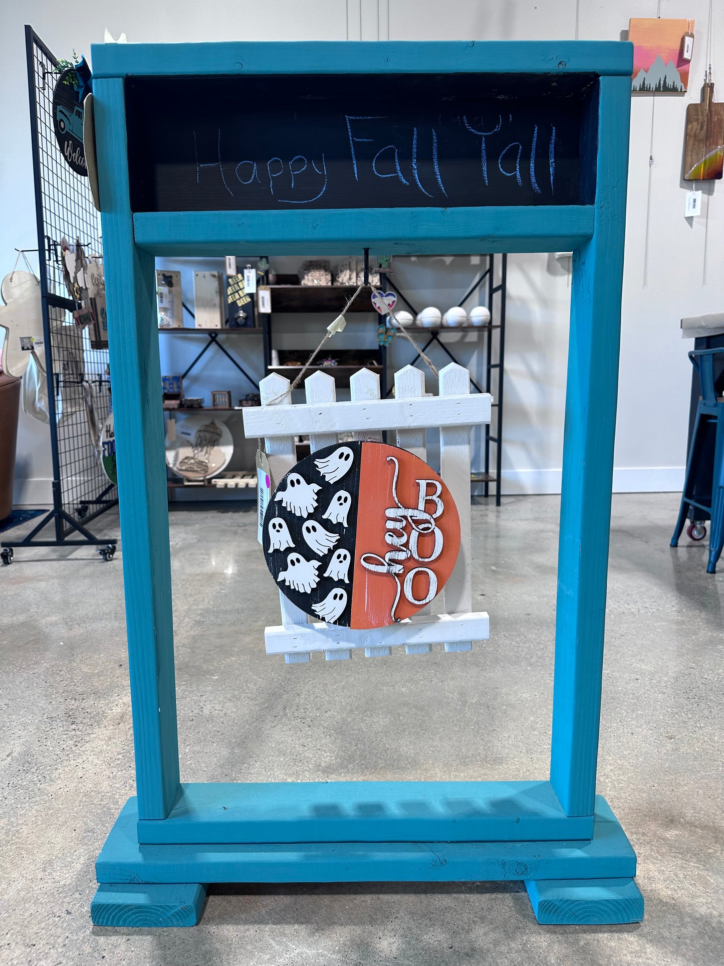 Teal porch decor that holds a hanging sign. Currently displaying a "hey boo" fall sign with ghosts on a picket fence holder.