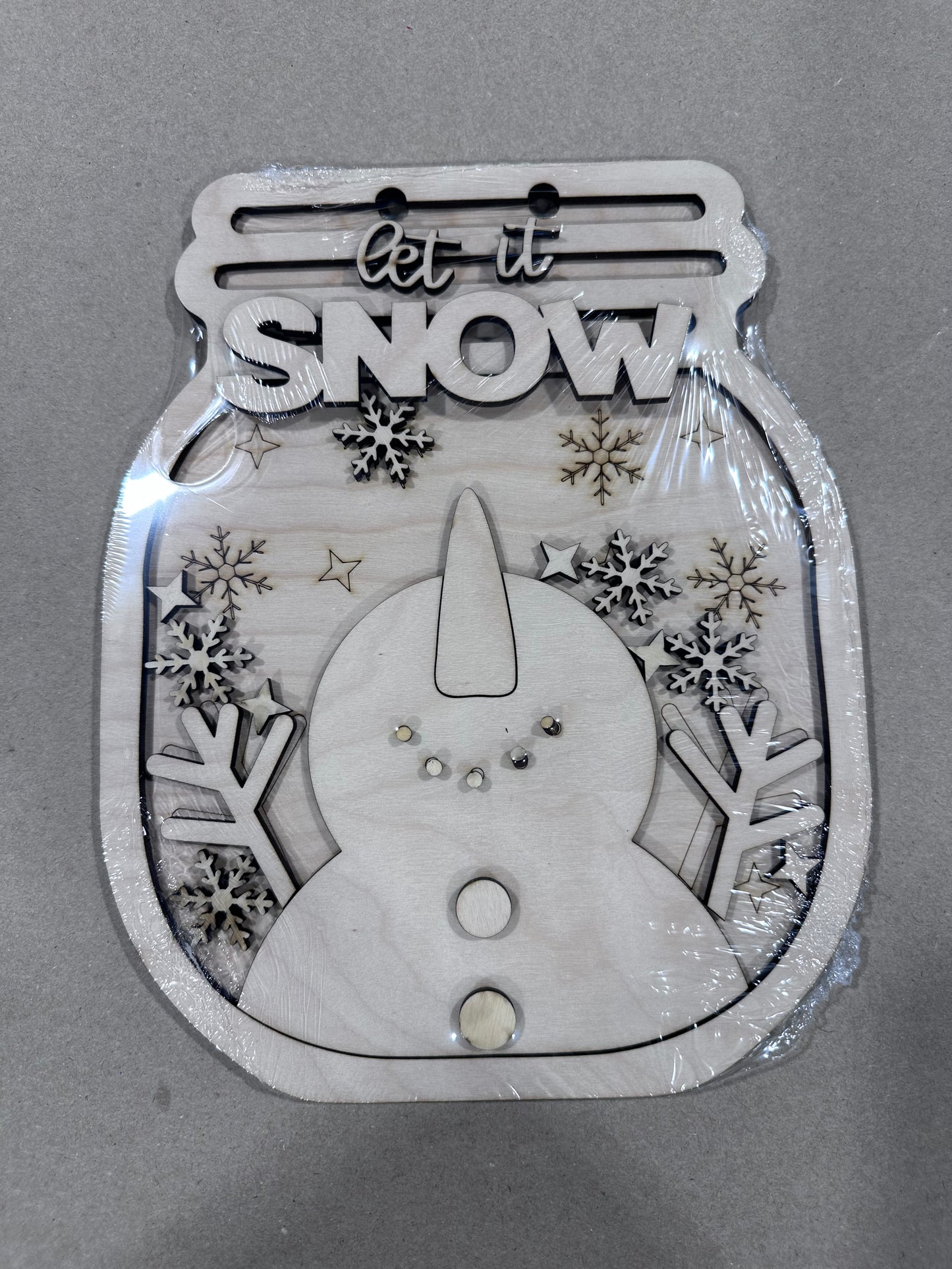 Wintery snowman in a mason jar-shaped wooden sign. Snowman is catching snowflakes, head tilted up.