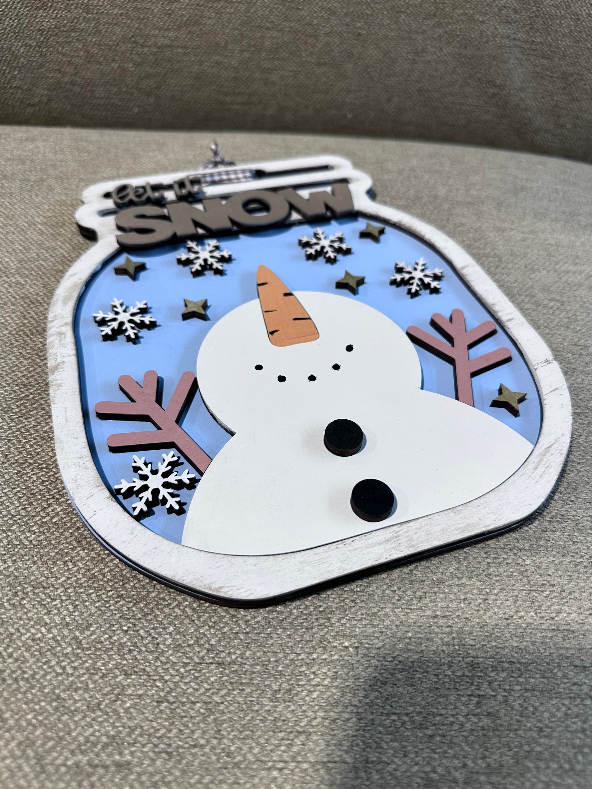 Decorative snowman sign with a jar shape, muted wintery tones, and sparkly details.
