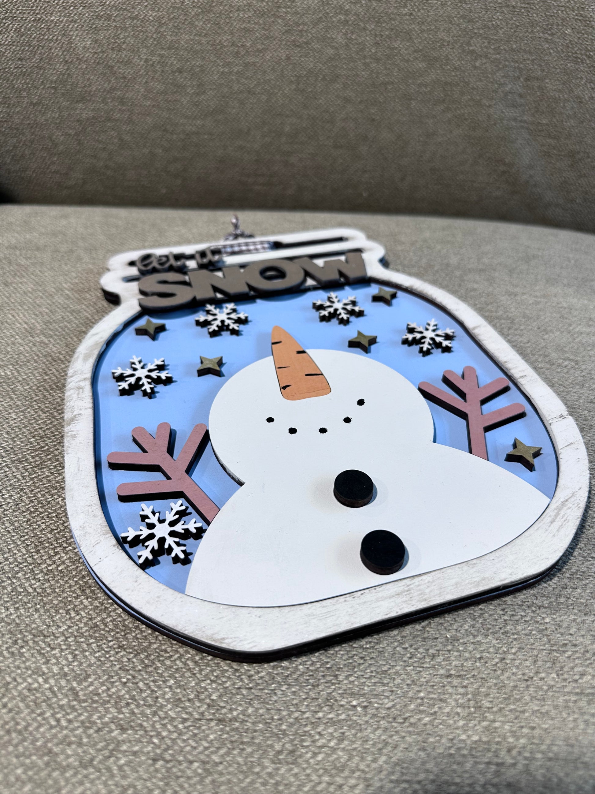 Decorative snowman sign with muted wintery tones.