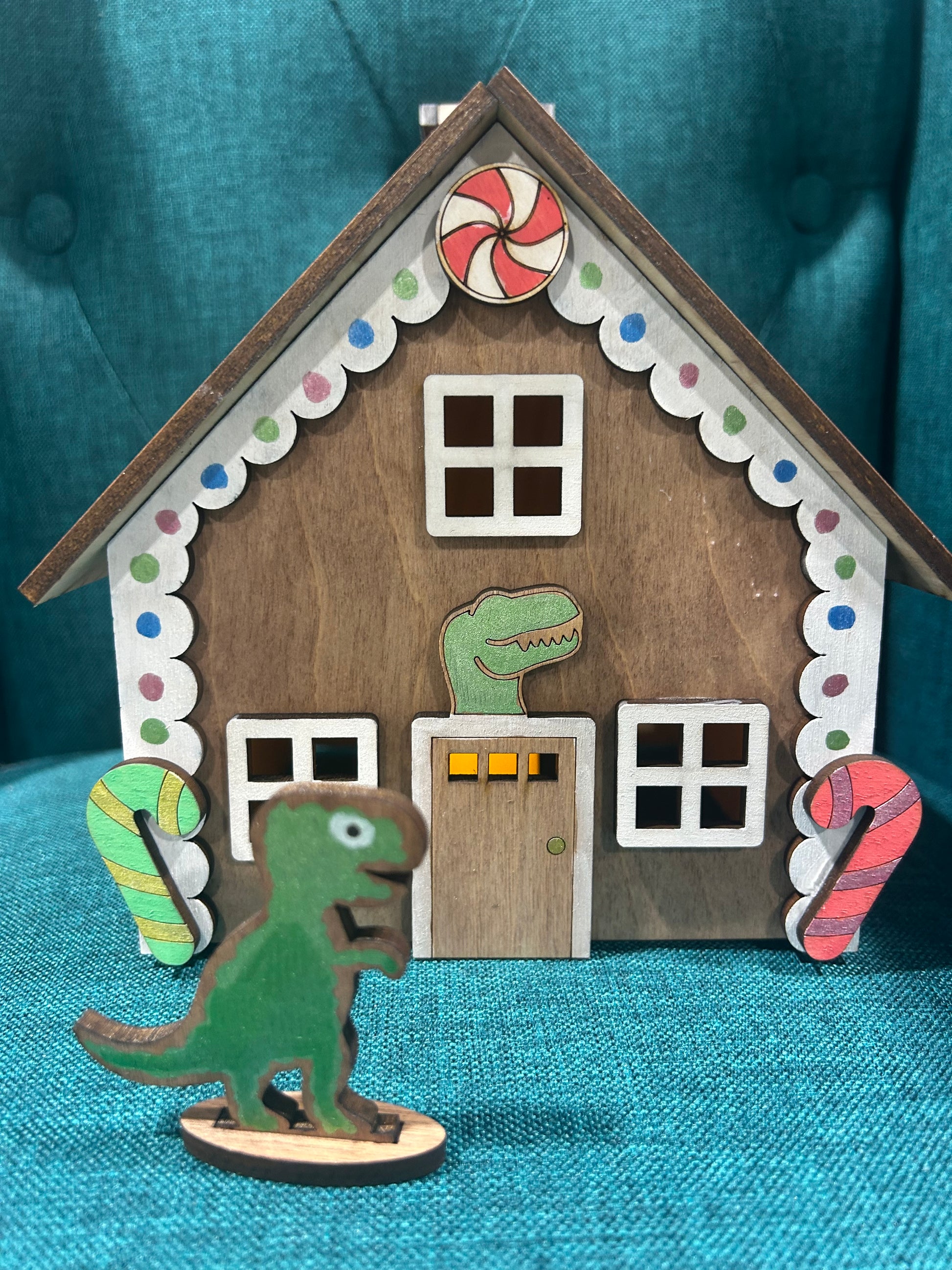 Laser cut gingerbread house featuring dinosaur figure