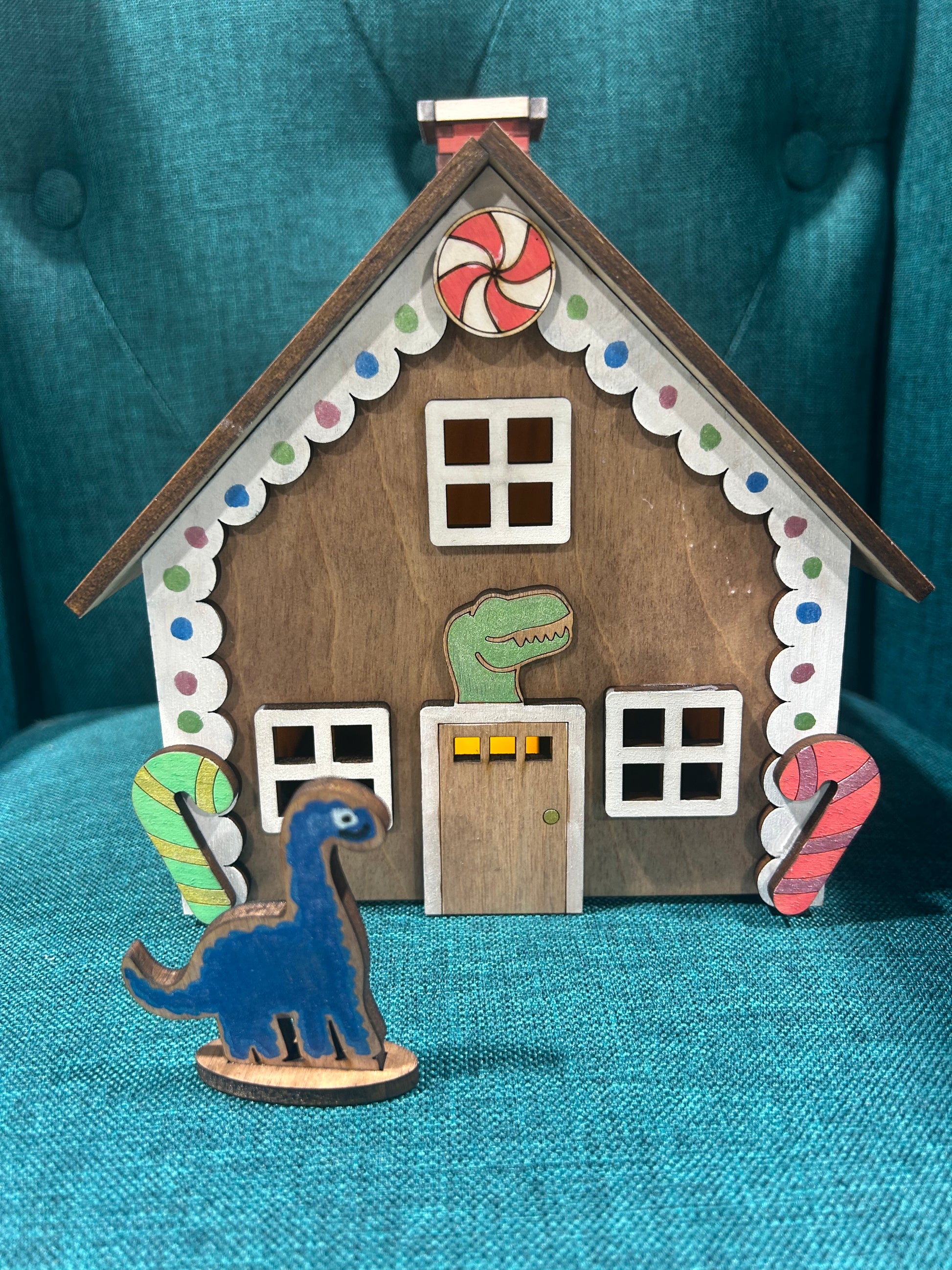 Laser cut gingerbread house featuring dinosaur figure