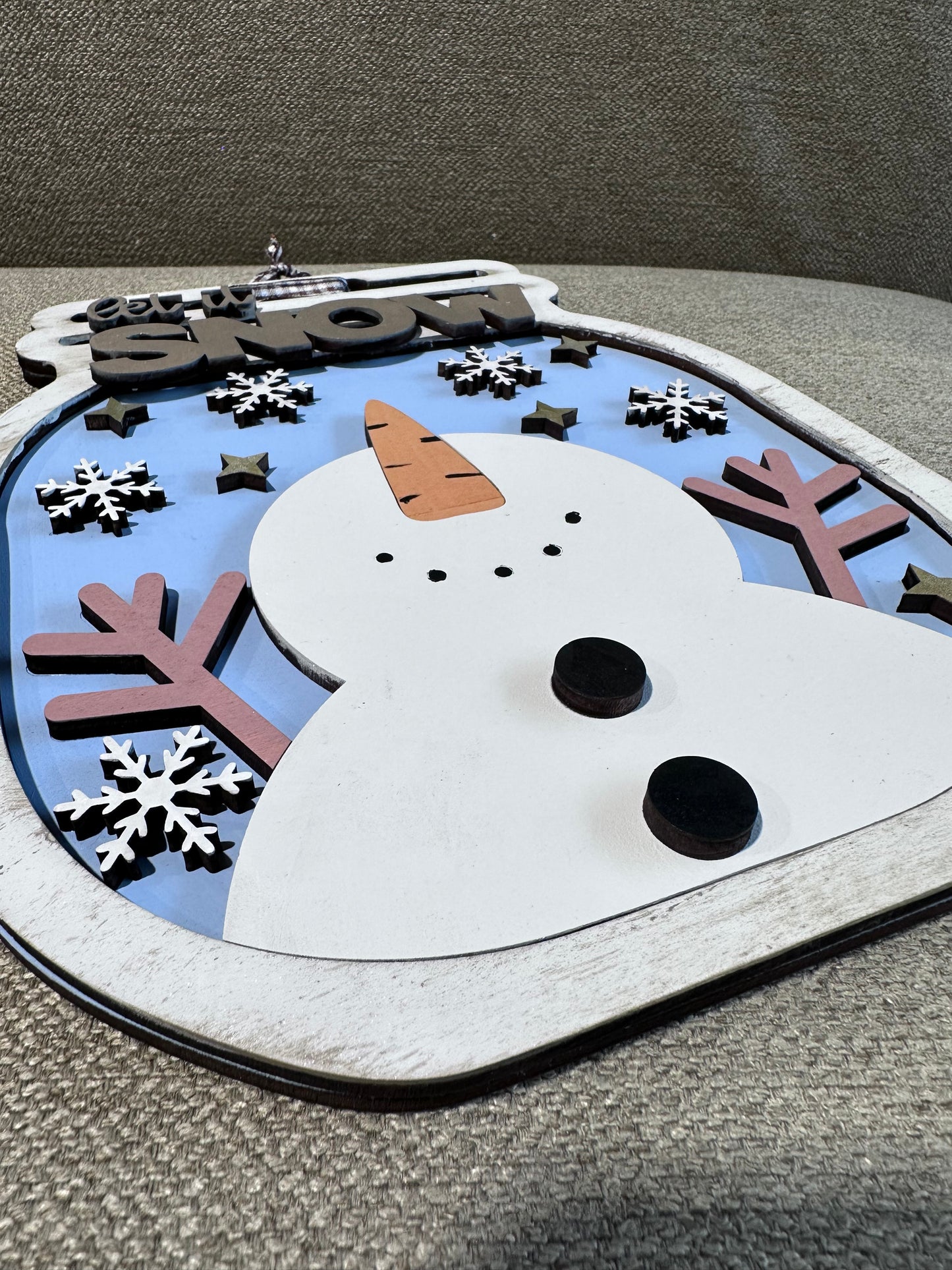 A close up of a snowman sign with silver dry brushing on a mason jar shaped wintery sign.