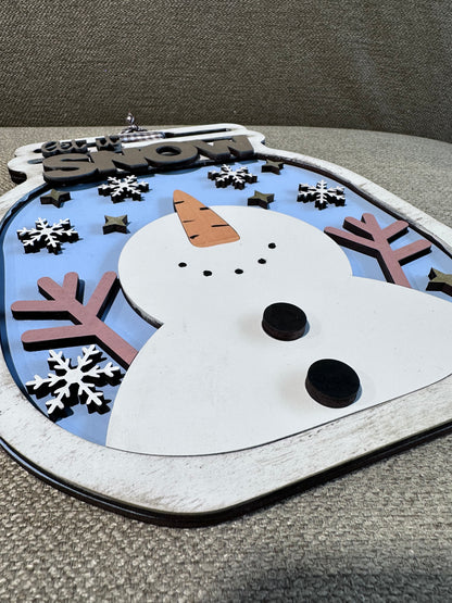 A close up of a snowman sign with silver dry brushing on a mason jar shaped wintery sign.